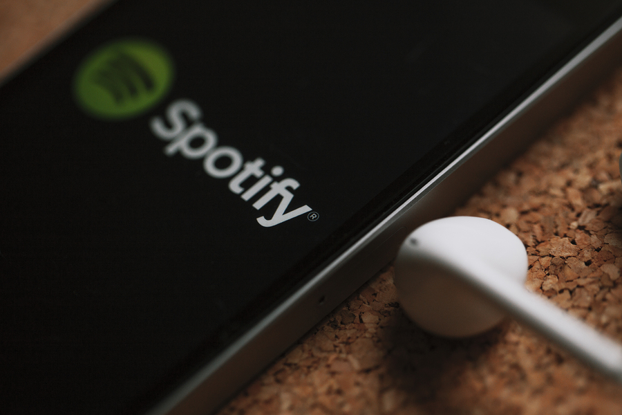 MALAGA, SPAIN - MARCH 5, 2018: Super macro detail of Mobile phone with Spotify logo in the screen and white earphones, placed on a cork panel.